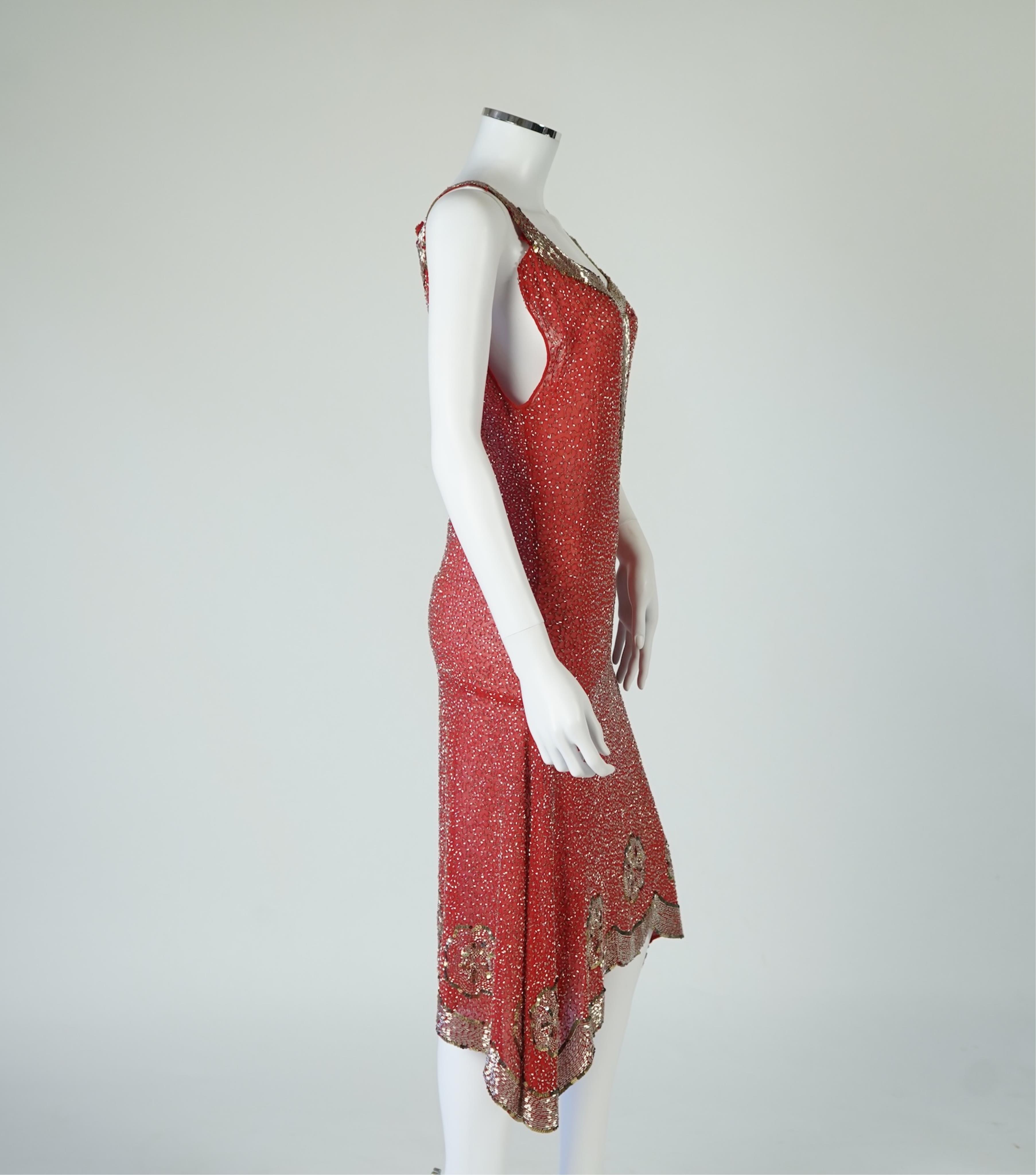 A 1920's red georgette beaded evening dress. Hand beaded and sequinned in white and gold, designed with a dropped waist, handkerchief points and wide beaded border with large stylistic floral motifs. Length 115cm. Condit